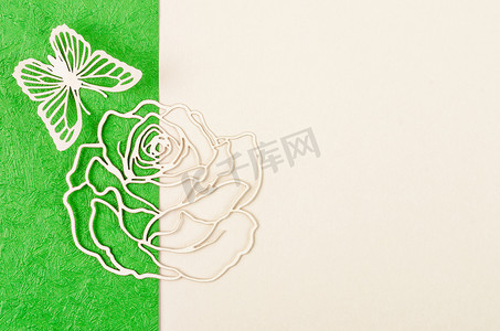 由雕刻纸制成的蝴蝶和玫瑰花，或在绿色和黄色背景上切割，并为您的文字或消息留出空间。