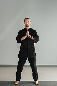气功摄影照片_穿着黑色和服的男子在室内练习气功能量练习