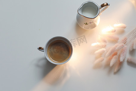 杯咖啡和牛奶壶在白色的木制背景，特写镜头。