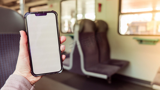 女手在火车上拿着白屏手机。