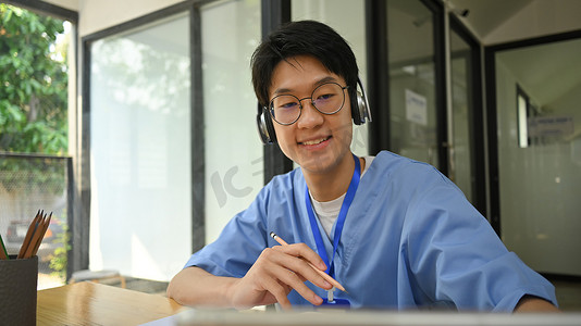 穿着蓝色磨砂服的年轻医生在网上给病人咨询。
