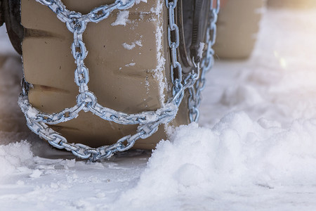 下雪安全摄影照片_带有安全防滑链的雪地车轮。