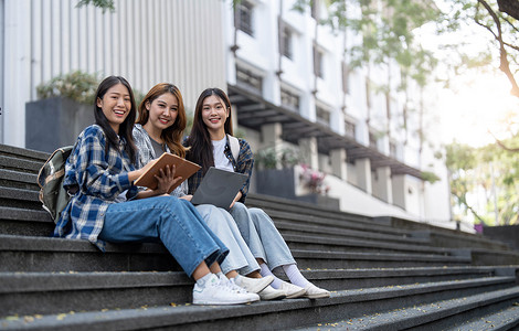 一群亚洲大学生在户外草地上读书并辅导特别班考试。