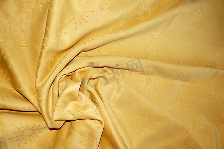 波浪曲线金色摄影照片_背景折叠中金色纺织材料的纹理