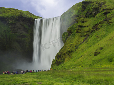 冰岛南部斯科加尔美丽的斯科加福斯瀑布，一群穿着色彩鲜艳的游客，长时间曝光运动模糊