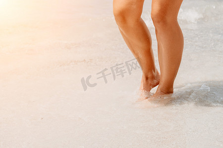 海滩旅行-在沙滩上行走的女人在白色的沙滩上留下脚印。