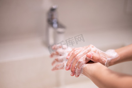 女人用肥皂在水龙头下洗手。