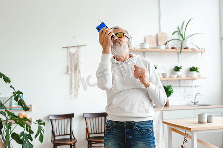 快乐的老人一边用耳机听音乐一边跳舞，复制空间和广告空位 — 活跃的老年人和享受舞蹈心情