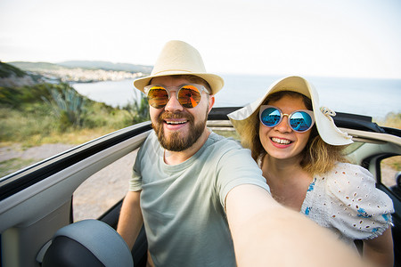 幸福美丽的情侣在度假时在路上驾驶敞篷车拍摄自拍照。