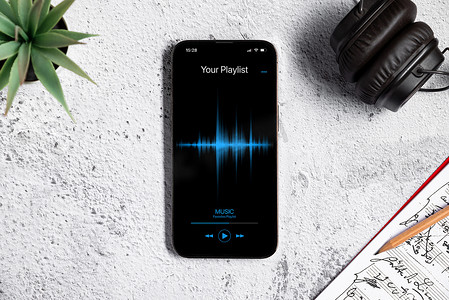 白石办公室桌面上带有音乐播放器应用程序的智能手机的顶视图
