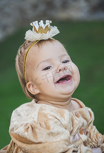 粉金王冠摄影照片_穿着公主服装、头上戴着王冠的迷人宝宝笑了