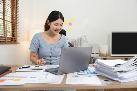 使用笔记本电脑和计算器从事财务工作的肖像会计亚洲女性，从事文书工作。