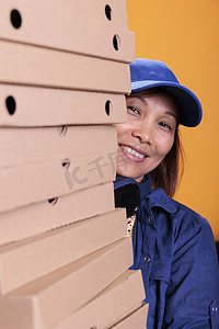 拿着披萨盒的微笑的亚洲高级送货员