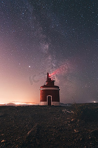 夜晚的灯塔，背后是银河