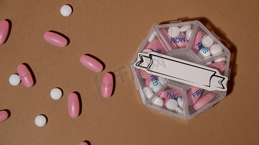 医疗药盒的特写镜头，其中装有每日服用白色粉色药物的药片和带有纸条的胶囊，复制文本模板模型的空间。
