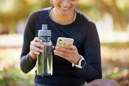 水瓶、智能手机和公园里的女性，用于健身网站应用程序、博客或社交媒体锻炼、锻炼或培训更新。