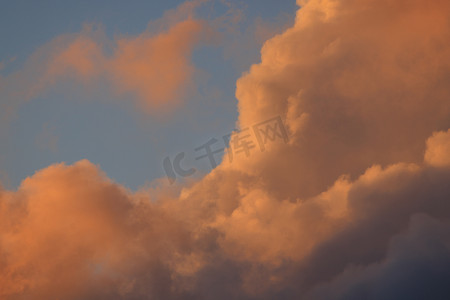 粉色天空云朵摄影照片_蓬松的粉红色云朵在清晨的阳光下翻滚
