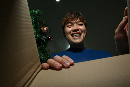 满意的年轻人打开纸箱，看着里面。