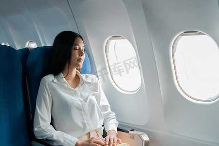 乘飞机旅行摄影照片_乘飞机旅行的女乘客睡在坐垫飞机上