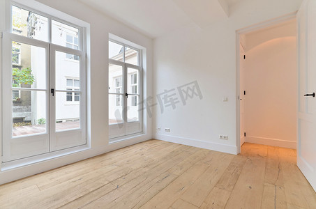 房间和门摄影照片_一间空荡荡的客厅，有白色的墙壁和木地板
