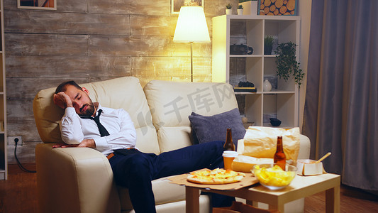 外卖零食摄影照片_劳累过度的商人睡在沙发上