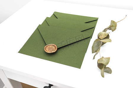 绿色信封，带有设计纸板和白色桌子和白色背景上的密封件