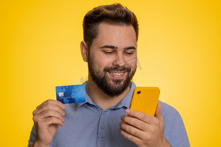 快乐的男人在网上购物时使用信用卡和智能手机转账