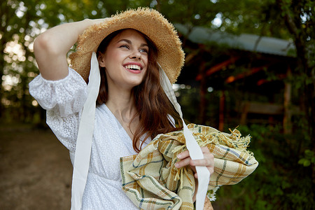 花纹免费摄影照片_一位笑容美丽的幸福女人的肖像站在大自然中，戴着柳条帽，手里拿着格子花呢