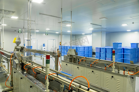 一家生产医用注射器和滴管的工厂，背景中有设备和蓝色容器