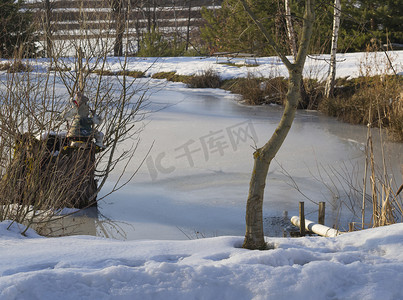 冰冻的池塘，树雪和阳光下的水精灵雕像