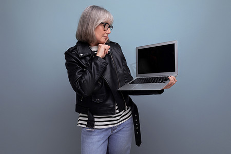 现代 60 年代成熟的老妇自由职业者，头发灰白，使用笔记本电脑，背景明亮