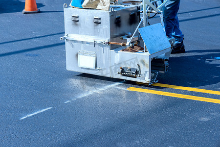 道路工人使用热熔划线机在沥青路面上涂漆线