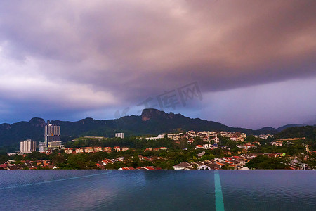 天空雨水摄影照片_傍晚的雨云给青山下的城市带来雨水