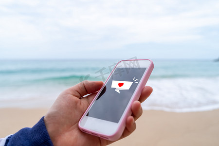 夏季海滩技术智能手机上聊天框图标上的心脏标志。