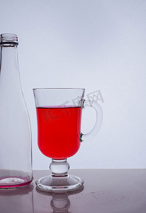 白色背景光效果中的红色液体进入玻璃杯