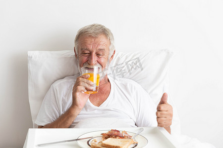 老年退休男性快乐地吃橙汁早餐