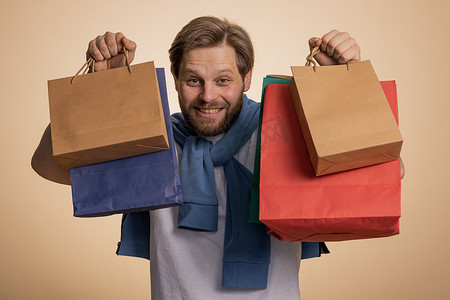 购物狂男人展示购物袋、广告折扣、微笑着对低价感到惊讶
