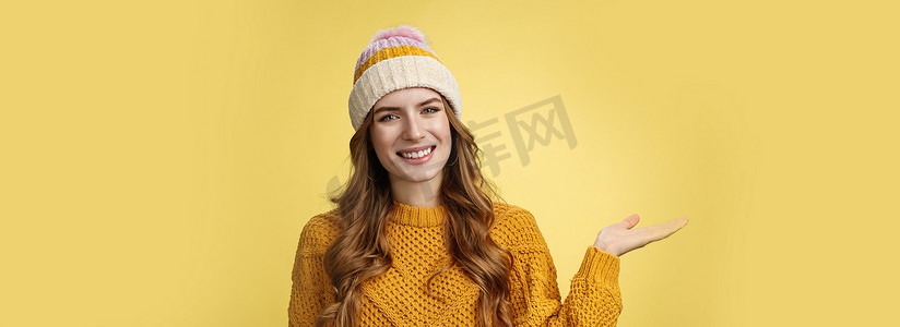 看上去友好、自信、迷人的年轻欧洲女性戴着冬帽、毛衣延伸手臂展示产品，欢迎客人快乐地微笑着进来，宣传复制空间