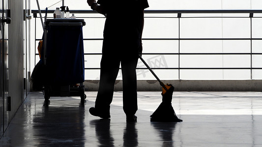 扫地男人摄影照片_清洁服务人员扫地的剪影