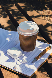 用工艺回收纸杯和纸质笔记本和无线耳机带走咖啡。