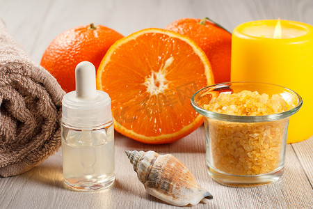 用两个完整的橙子切橙子、毛巾、贝壳、装有芳香油的瓶子