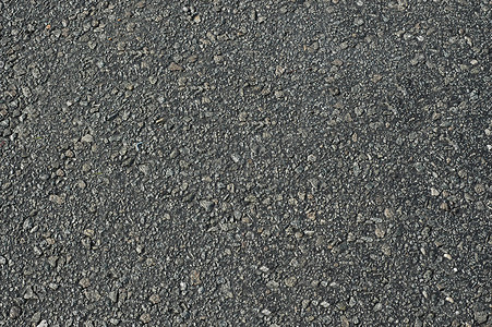 有不平坦的深灰色织地不很细表面的沥青路面。背景
