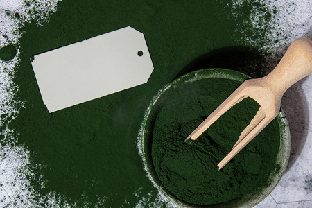功能食品摄影照片_碗中的蓝绿藻小球藻和螺旋藻粉，带有空纸条模拟复制空间。