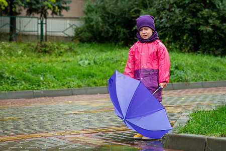 孩子撑着伞在雨中行走。