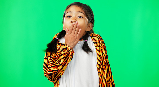 工作室背景上的脸、绿色屏幕和穿着老虎服装的女孩，惊喜和手放在嘴上。