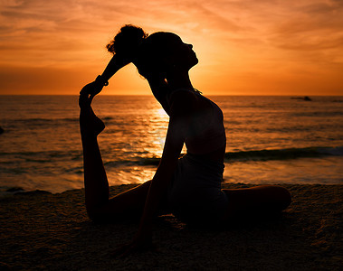 瑜伽摄影照片_普拉提、瑜伽和日出时海滩上的女性剪影，进行锻炼、训练和健身锻炼。
