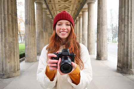 在旅行期间摄影照片_微笑的旅游摄影师，在旅行期间拍照，拿着专业相机并拍照