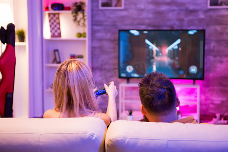 年轻夫妇放松玩在线射击游戏的后视图