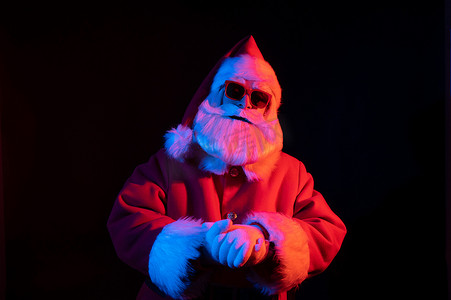 庆祝霓虹灯摄影照片_霓虹灯下戴着太阳镜的圣诞老人肖像。