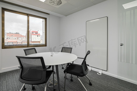 人围着一张圆桌图摄影照片_董事办公室设有圆桌和灰色色调的椅子，办公室会议室设有大窗户和自然光。